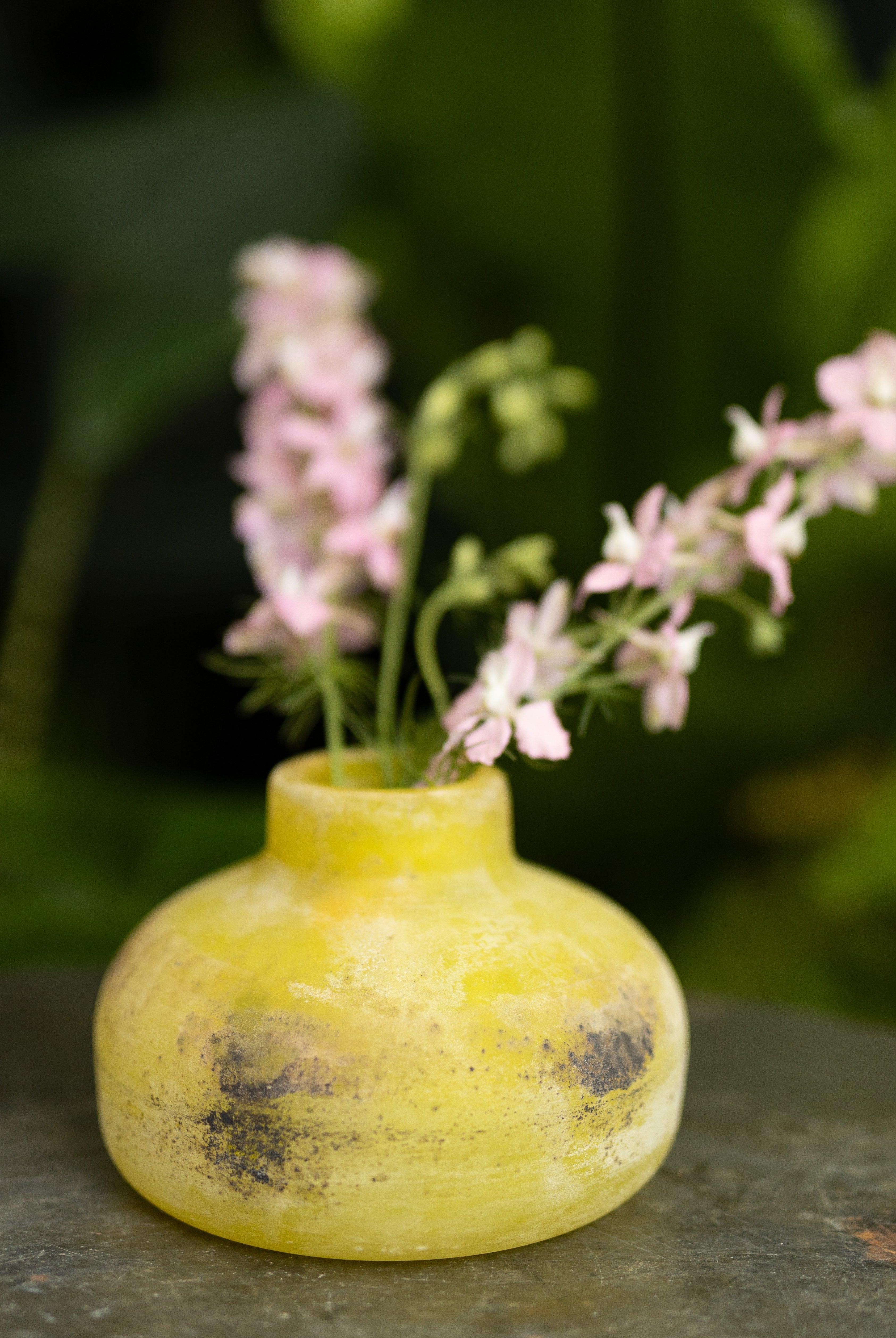 Yellow Scavo Murano vase with pink flowers on a dark surface
