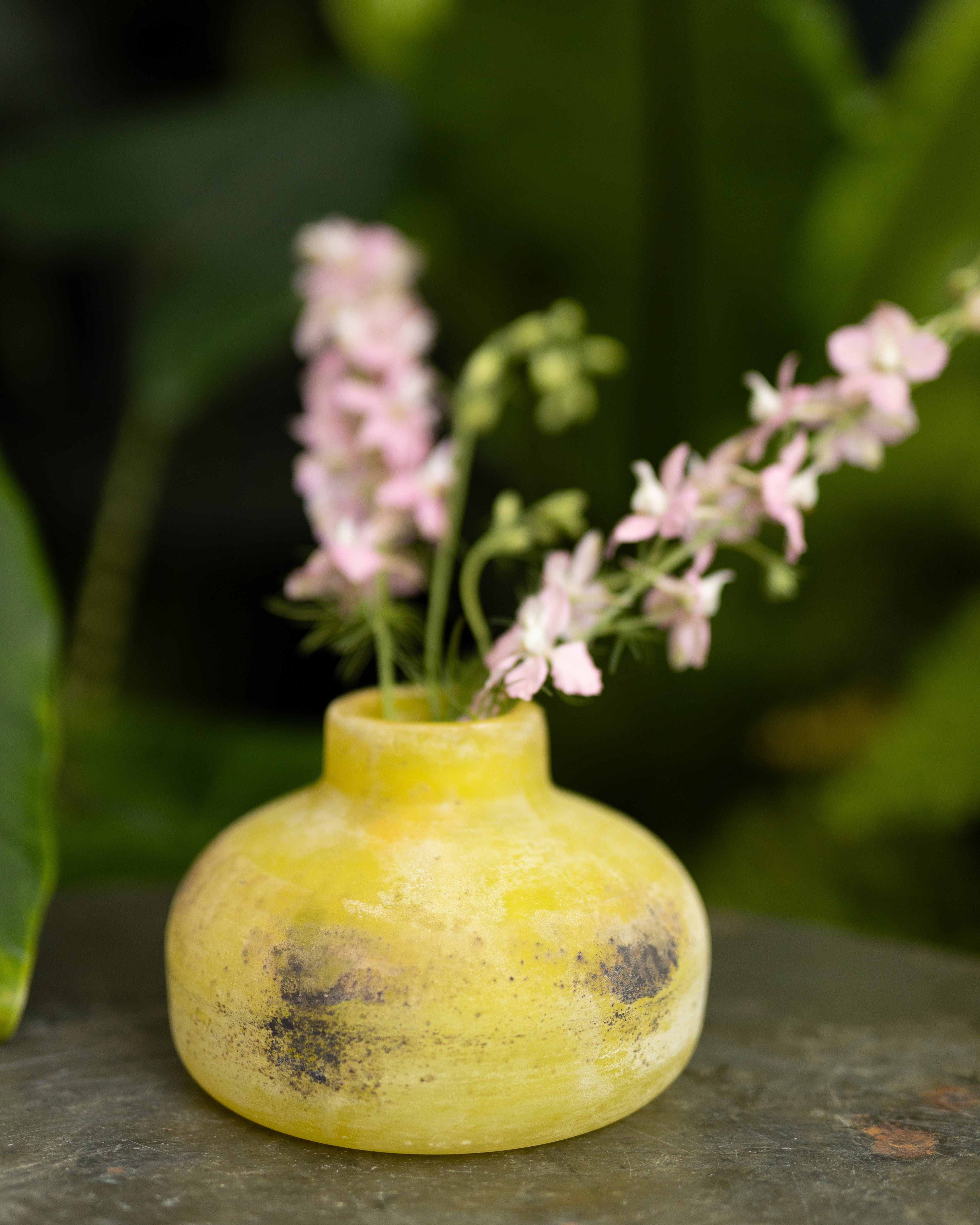 Yellow Scavo Murano vase with pink flowers on a dark surface