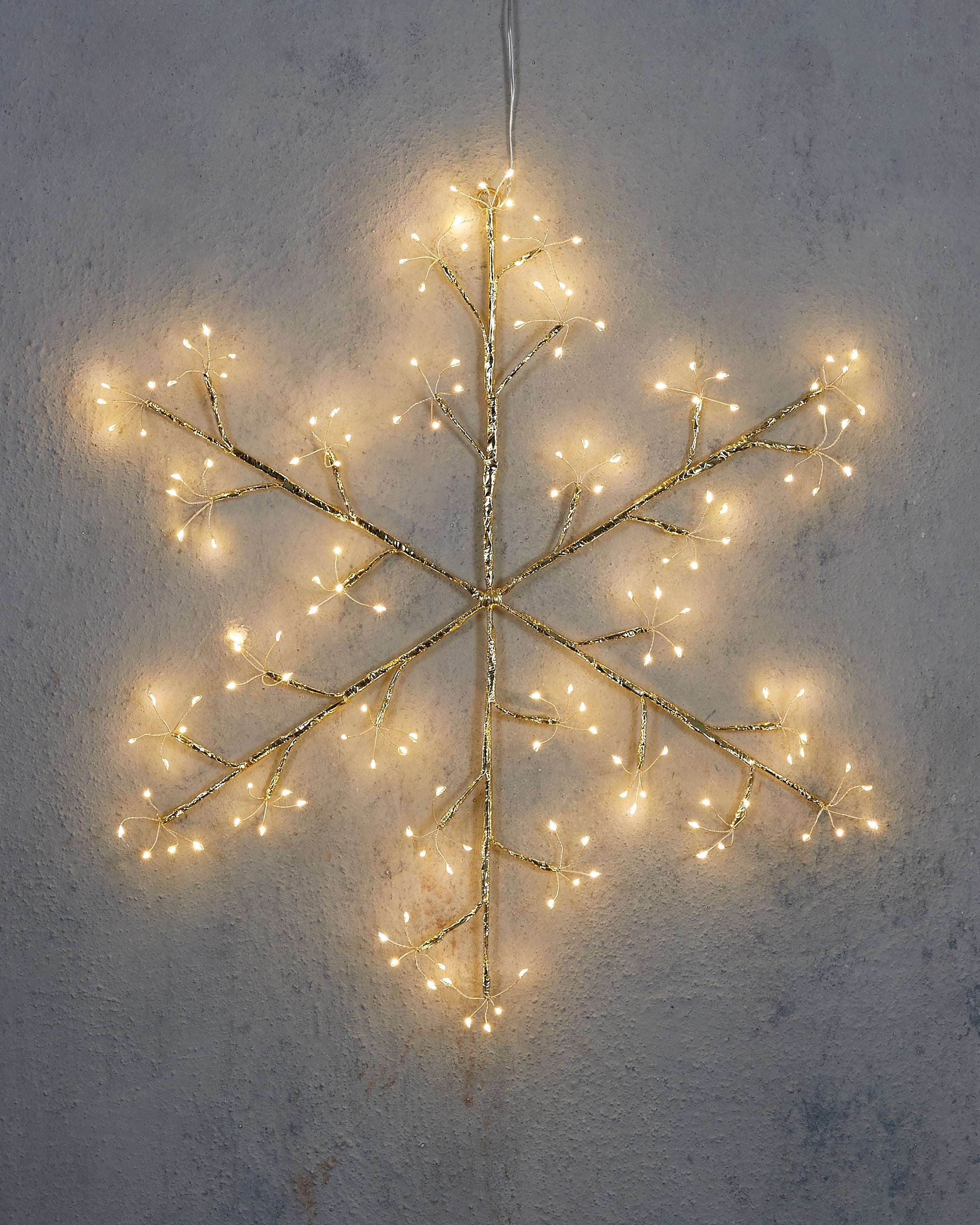 Decorative light fixture shaped like a snowflake on a textured wall.
