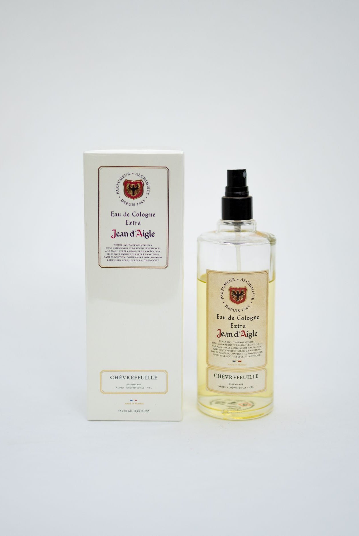A bottle of Jean d'Aigle Eau de Cologne Elixir next to its white packaging box, set against a plain light gray background.