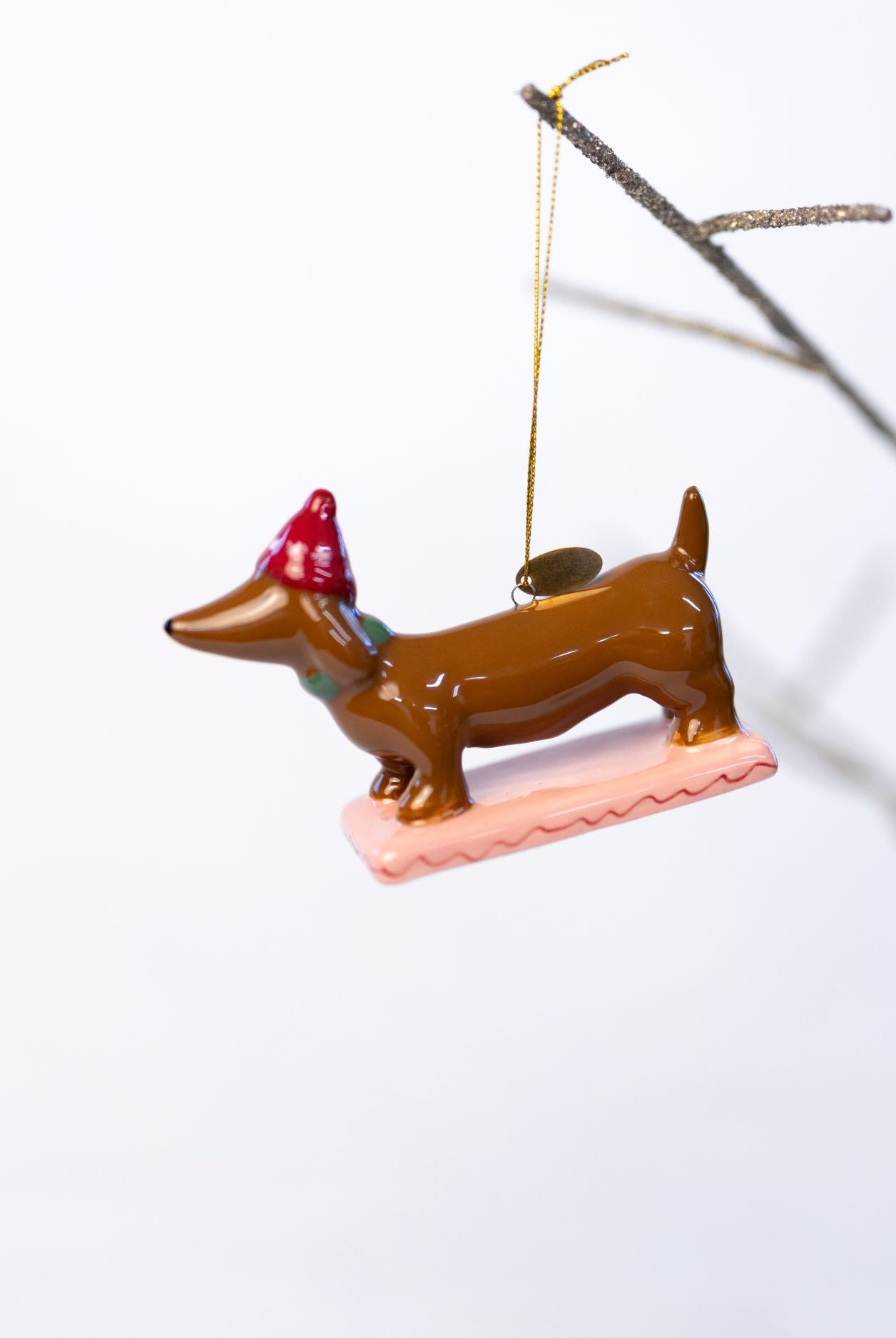 Decorative dachshund ornament with a red hat on a white background