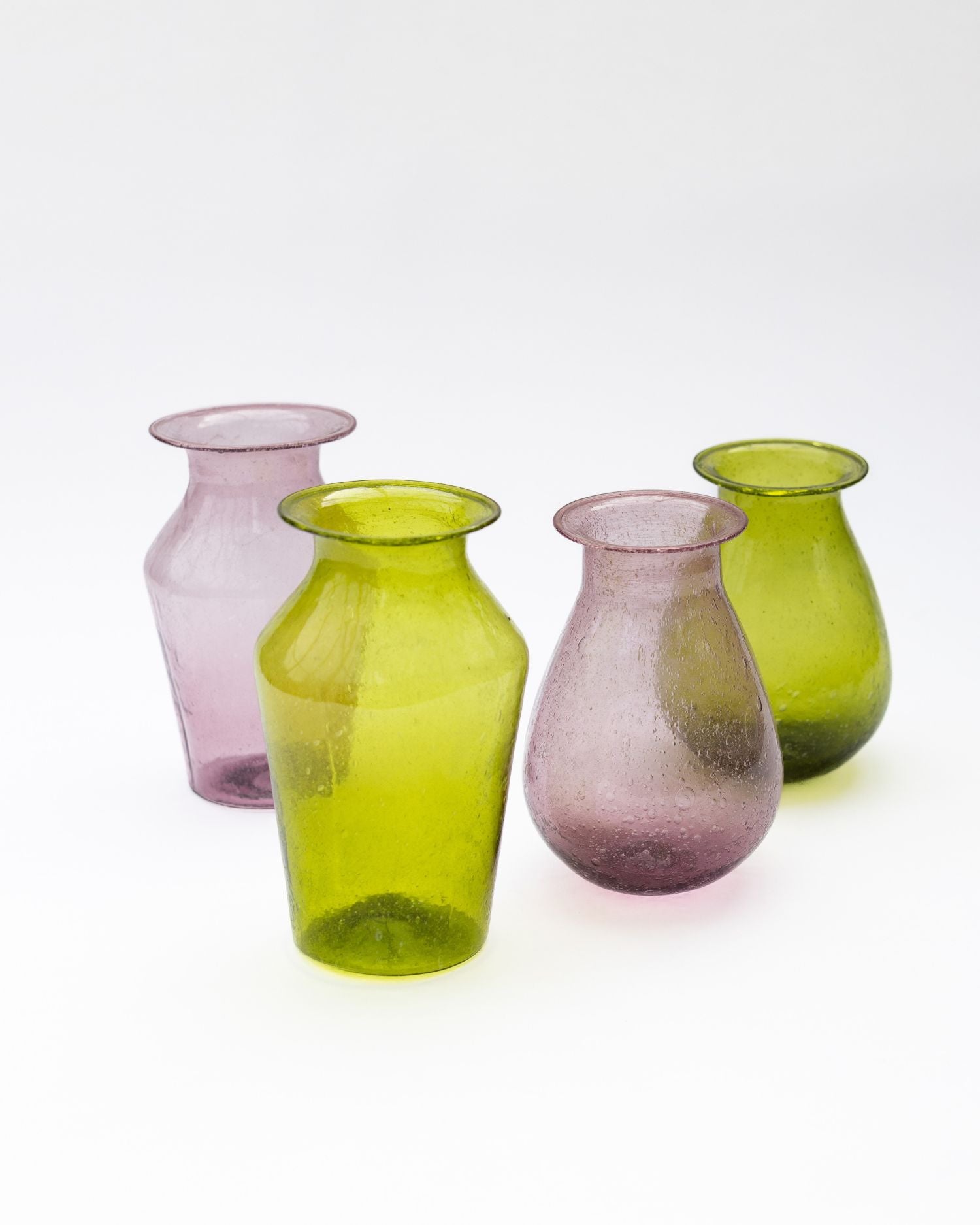 Four glass vases in green and pink on a white background