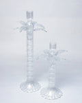 Two clear palm tree-shaped candle holders on a light gray background