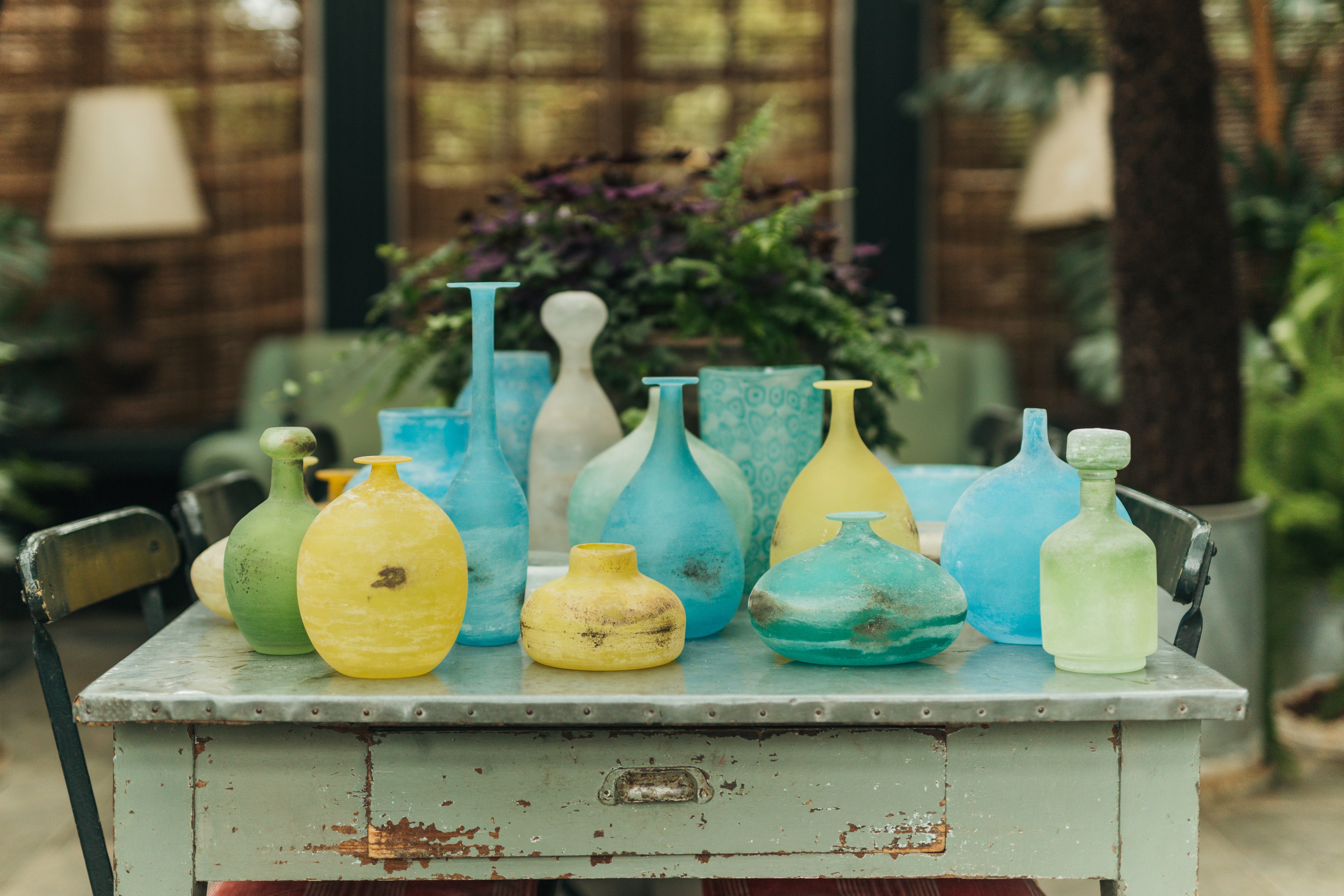 Colorful glass vases on a rustic table outdoors