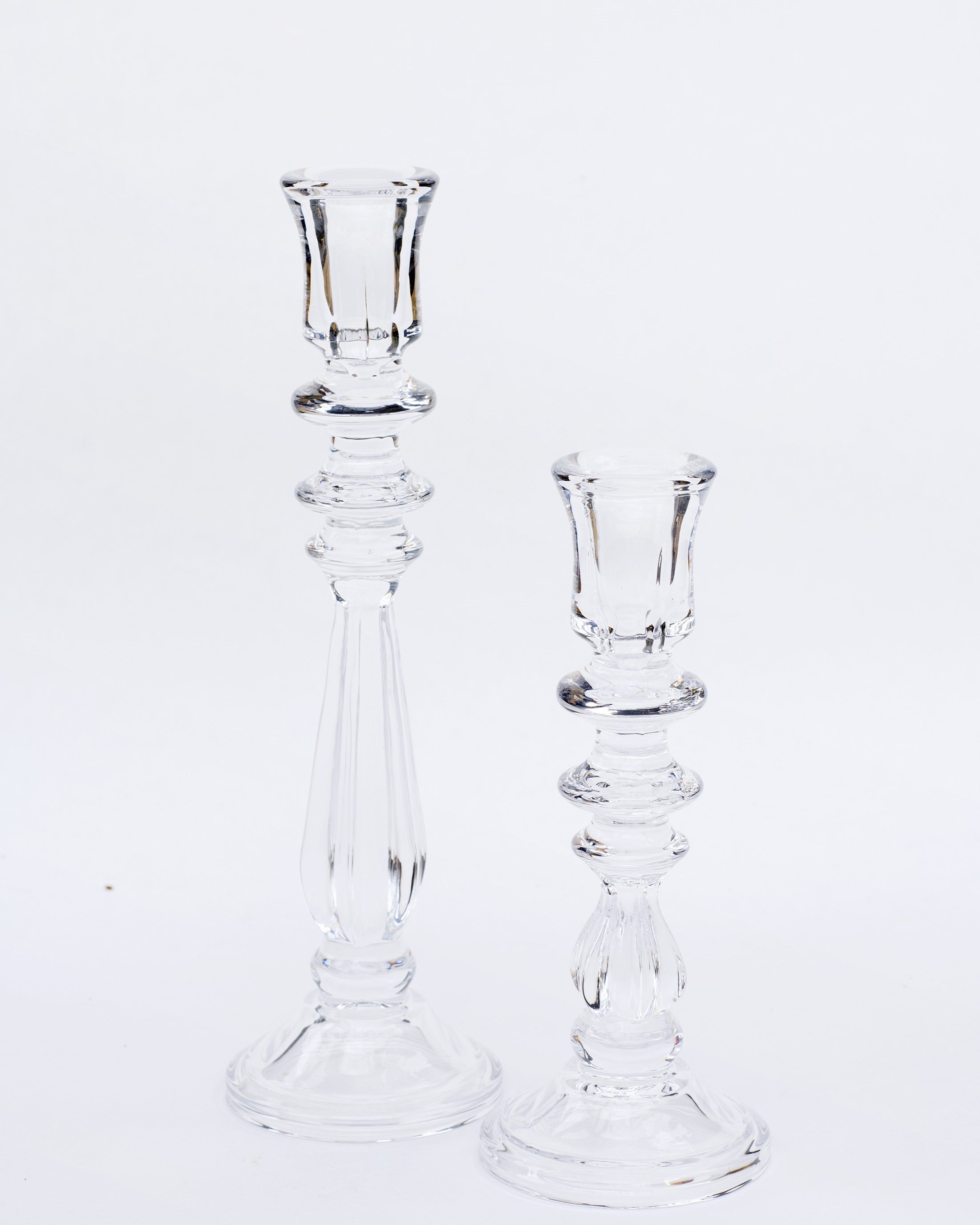 Two clear glass candlesticks of different sizes on a white background, designed in a simple and elegant style.
