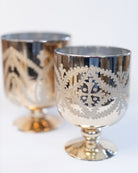 Two silver goblets with intricate designs on a white background