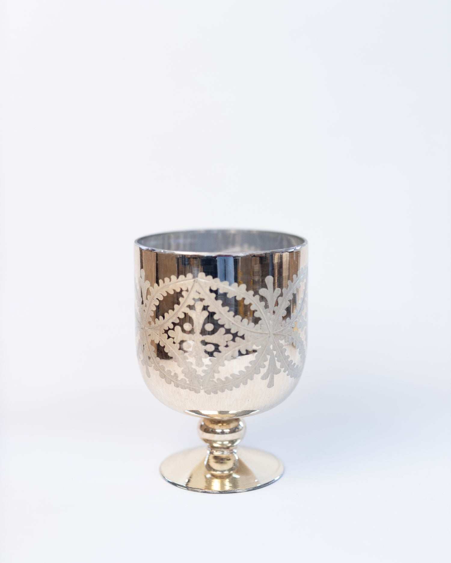 Silver goblet with intricate cut-out design on a white background
