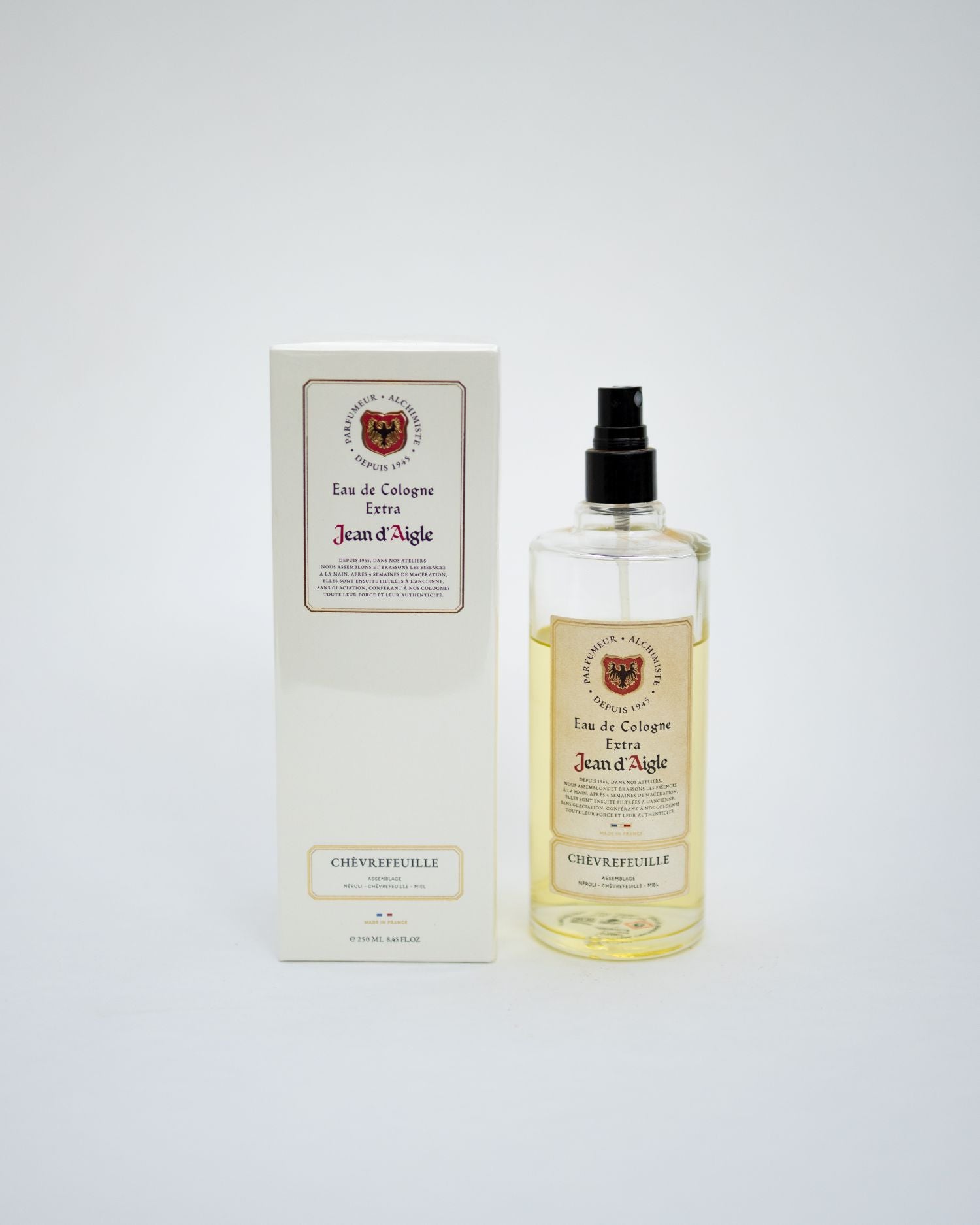 A bottle of Jean d'Aigle Eau de Cologne Elixir next to its white packaging box, set against a plain light gray background.