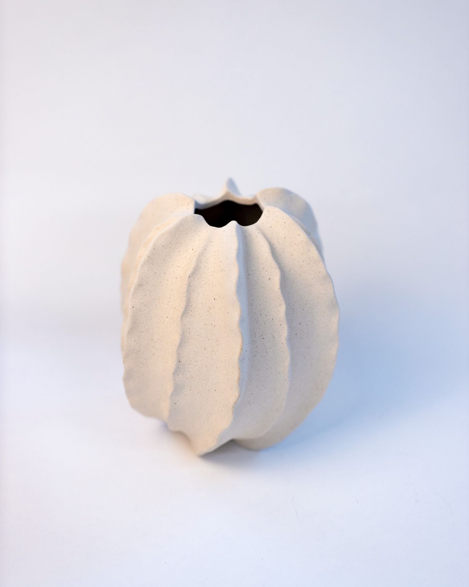 White ceramic vase with textured surface on a light blue background