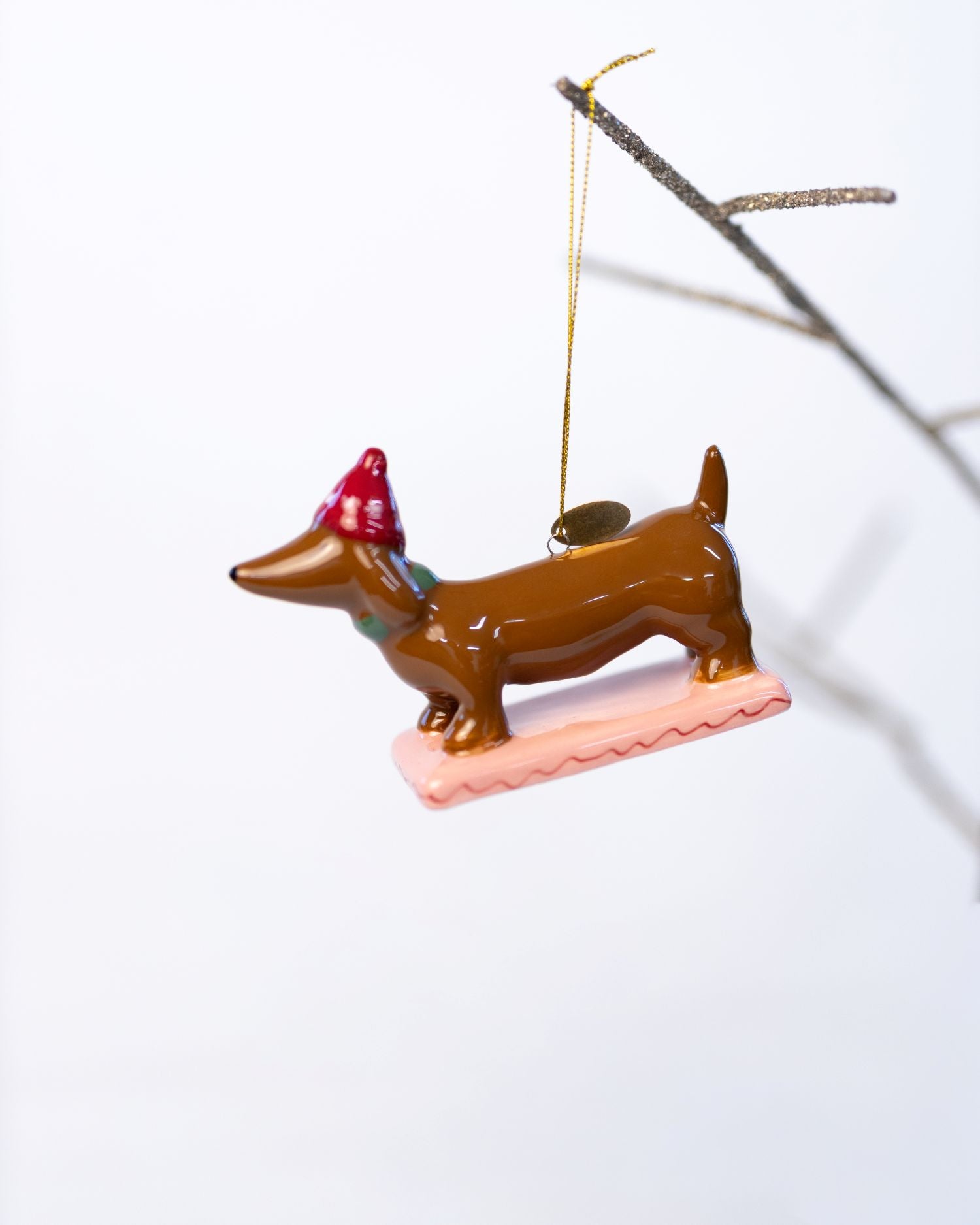 Decorative dachshund ornament with a red hat on a white background