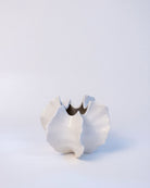 White ceramic vase with a unique design on a light gray background