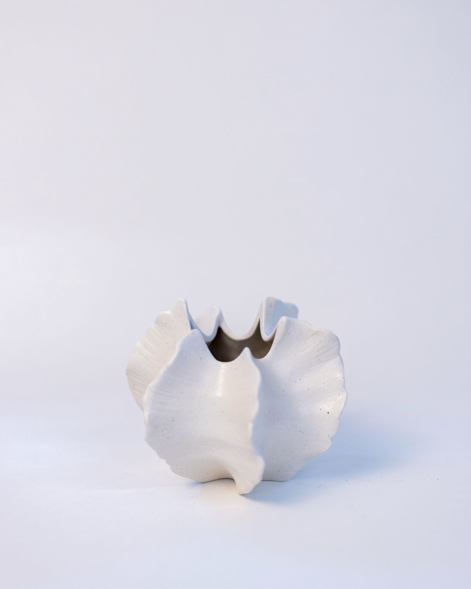 White ceramic vase with a unique design on a light gray background